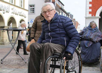 Herr im Rollstuhl vor dem Rathaus in der Fußgängerzone